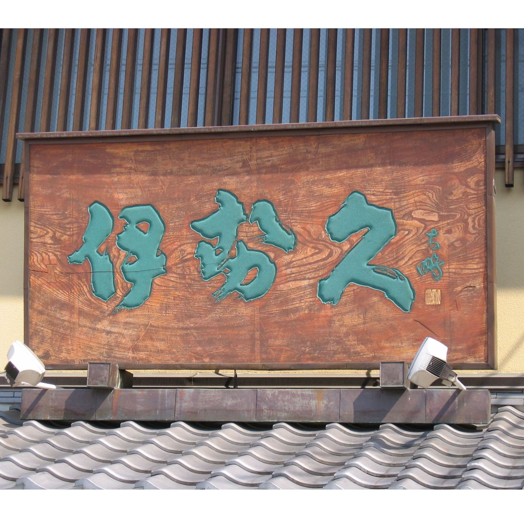 屋根の上に木製看板、伝統的な和菓子屋の看板で文字の色は緑青を使っている