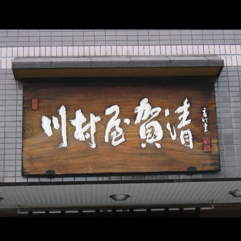 和菓子店の看板で木の板に彫った白い文字で壁に取り付けてある看板
