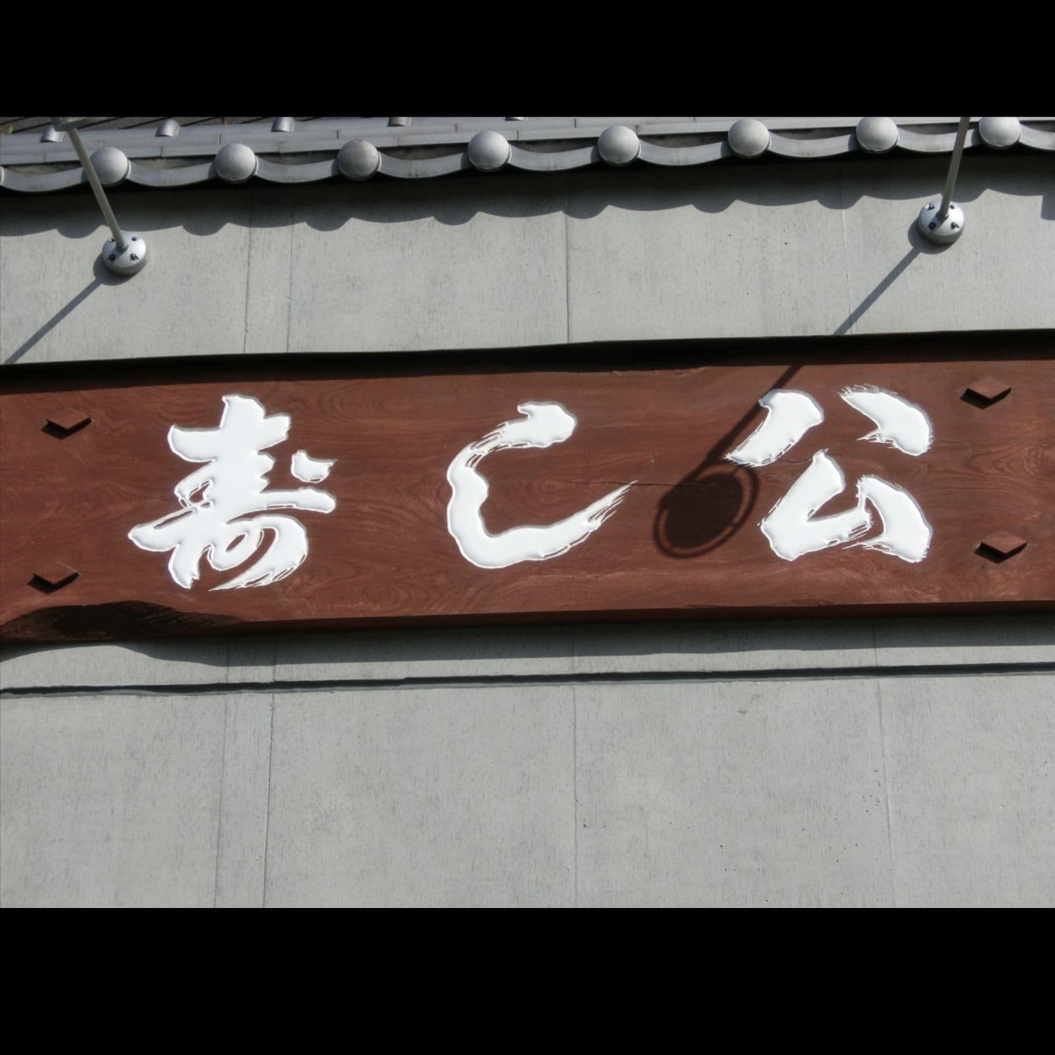 木の板に白い文字で屋号が彫ってあるお寿司屋さんの看板