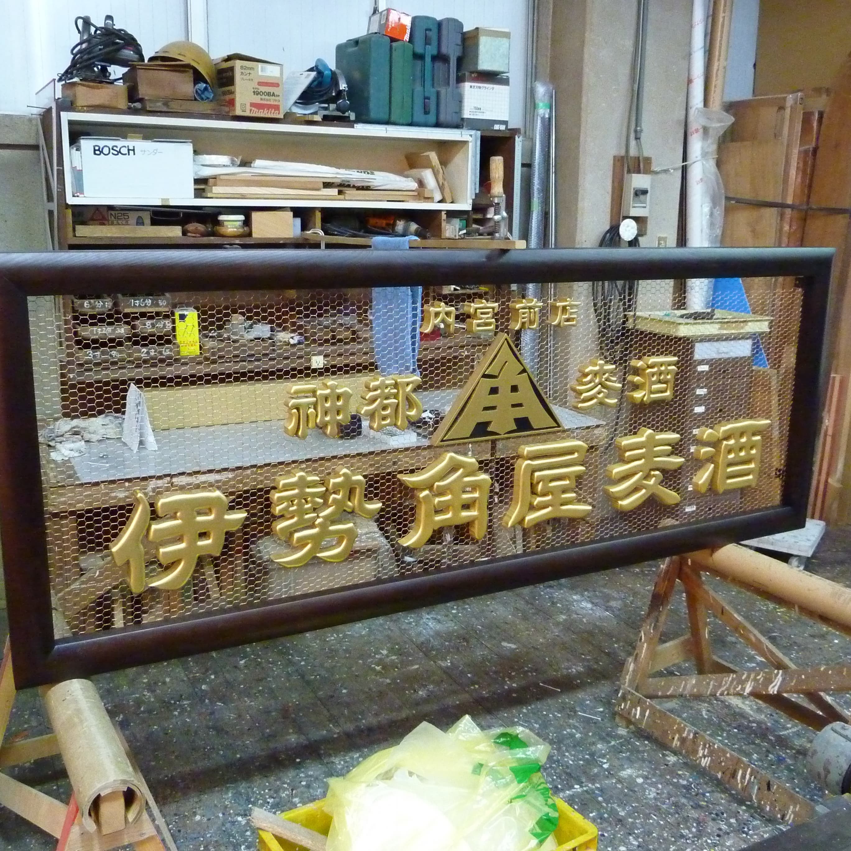 木の枠に銅網背景、金色の文字の看板