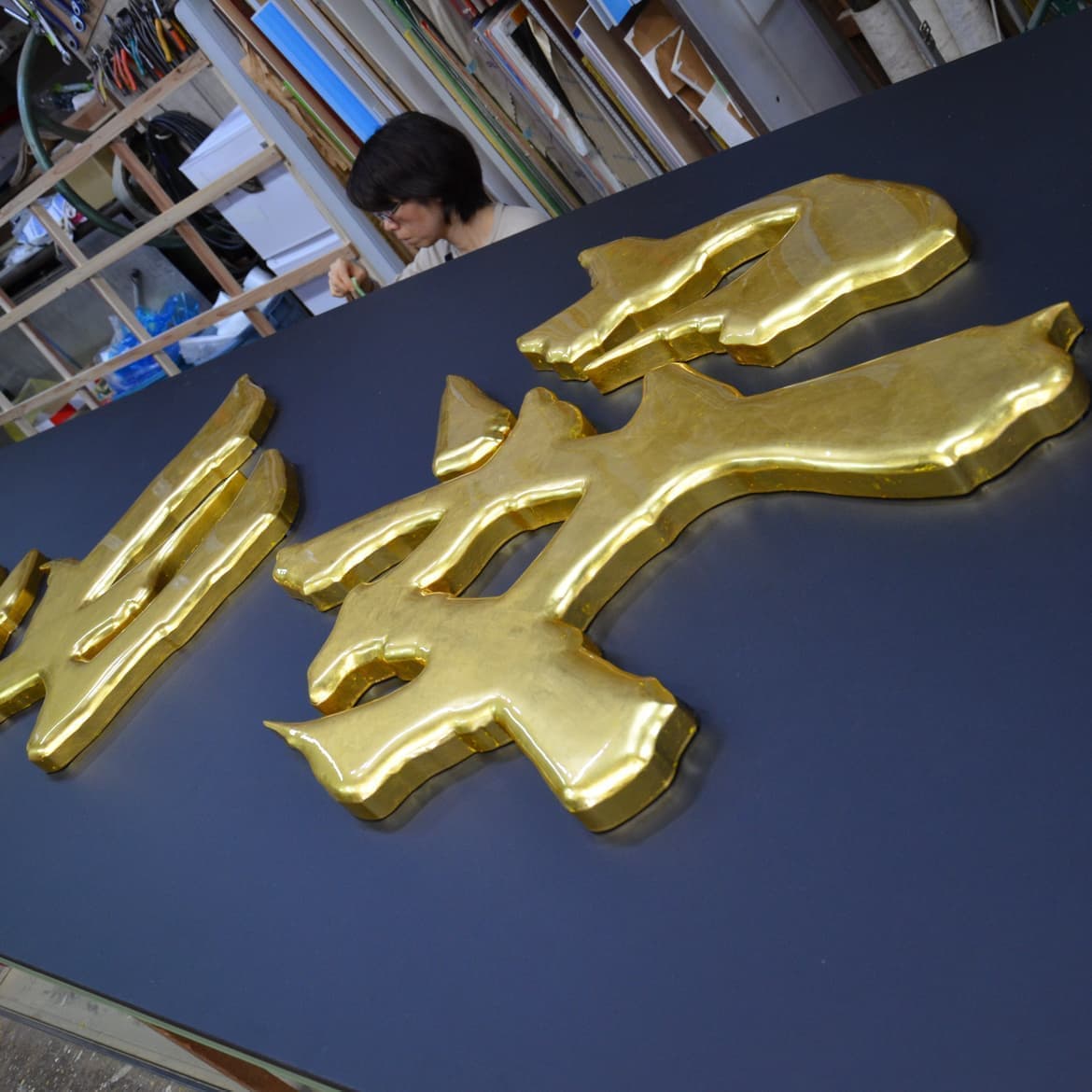 黒い看板の背景に金色の切り抜き文字が映える干物店の看板