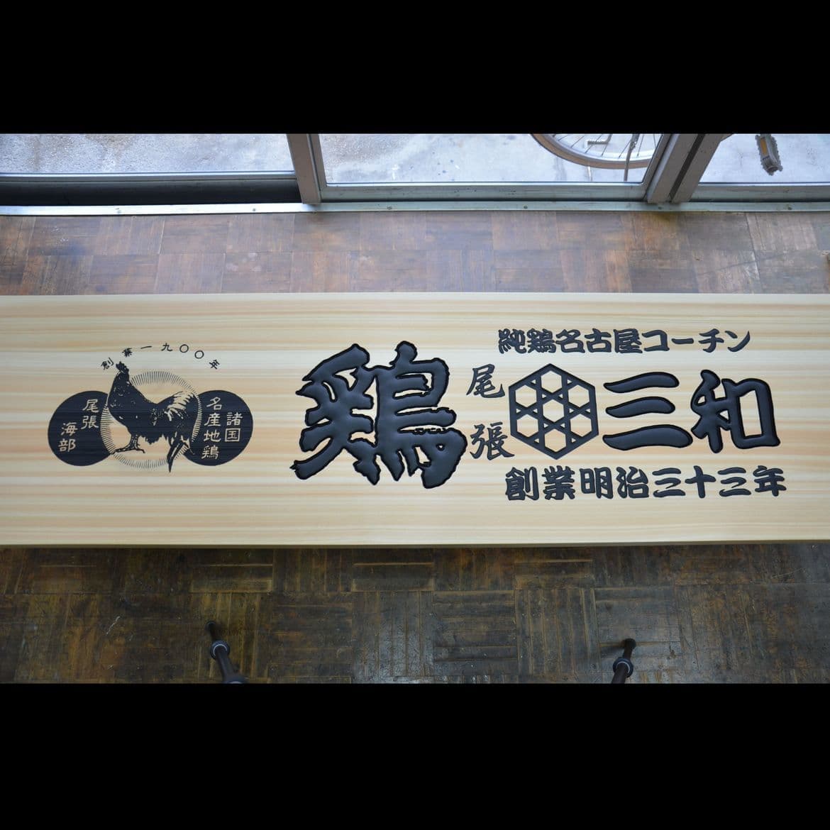 檜の白木に黒文字の彫刻の鶏料理店の看板
