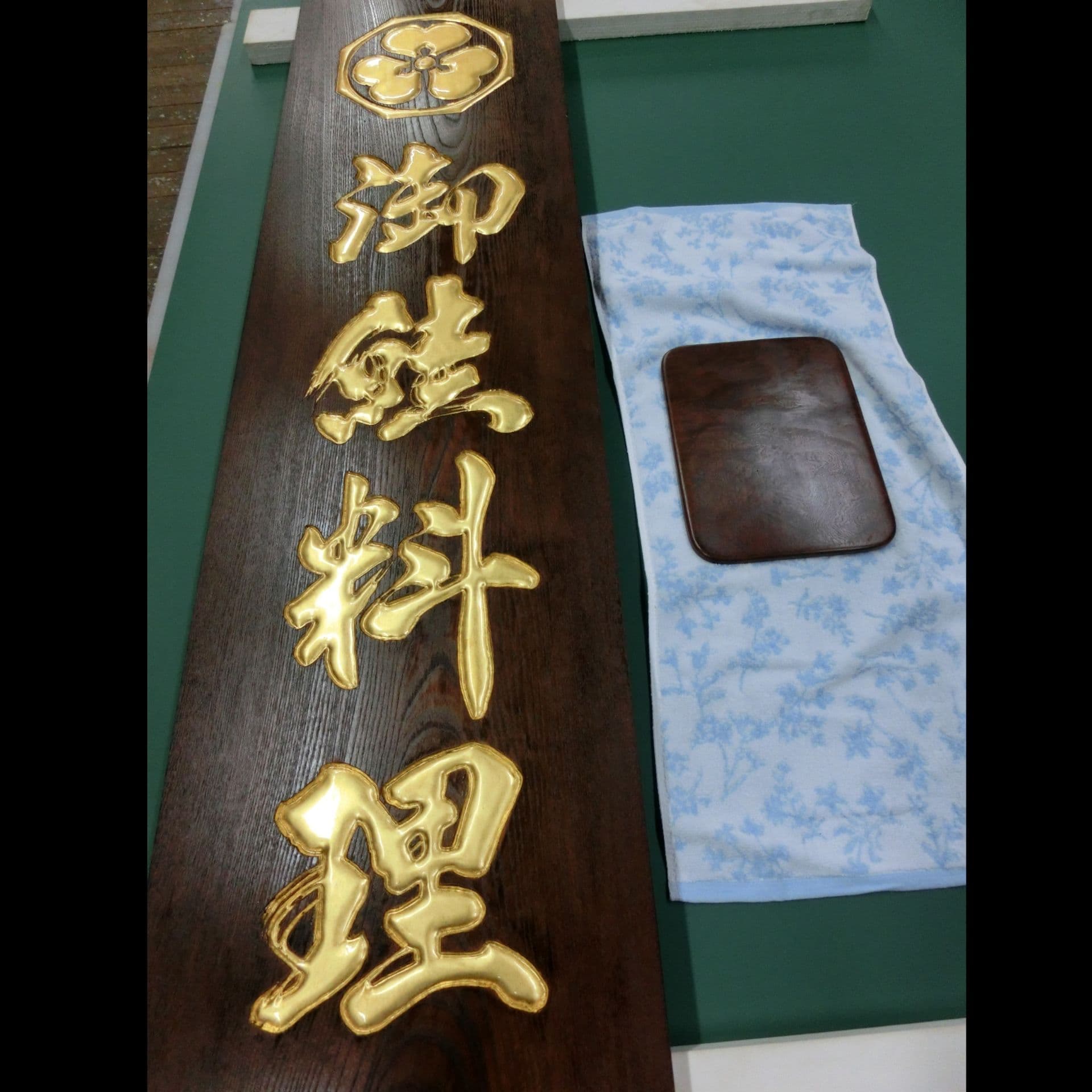濃い色の木の板に金色の文字、和風の雰囲気の鮭料理店の看板