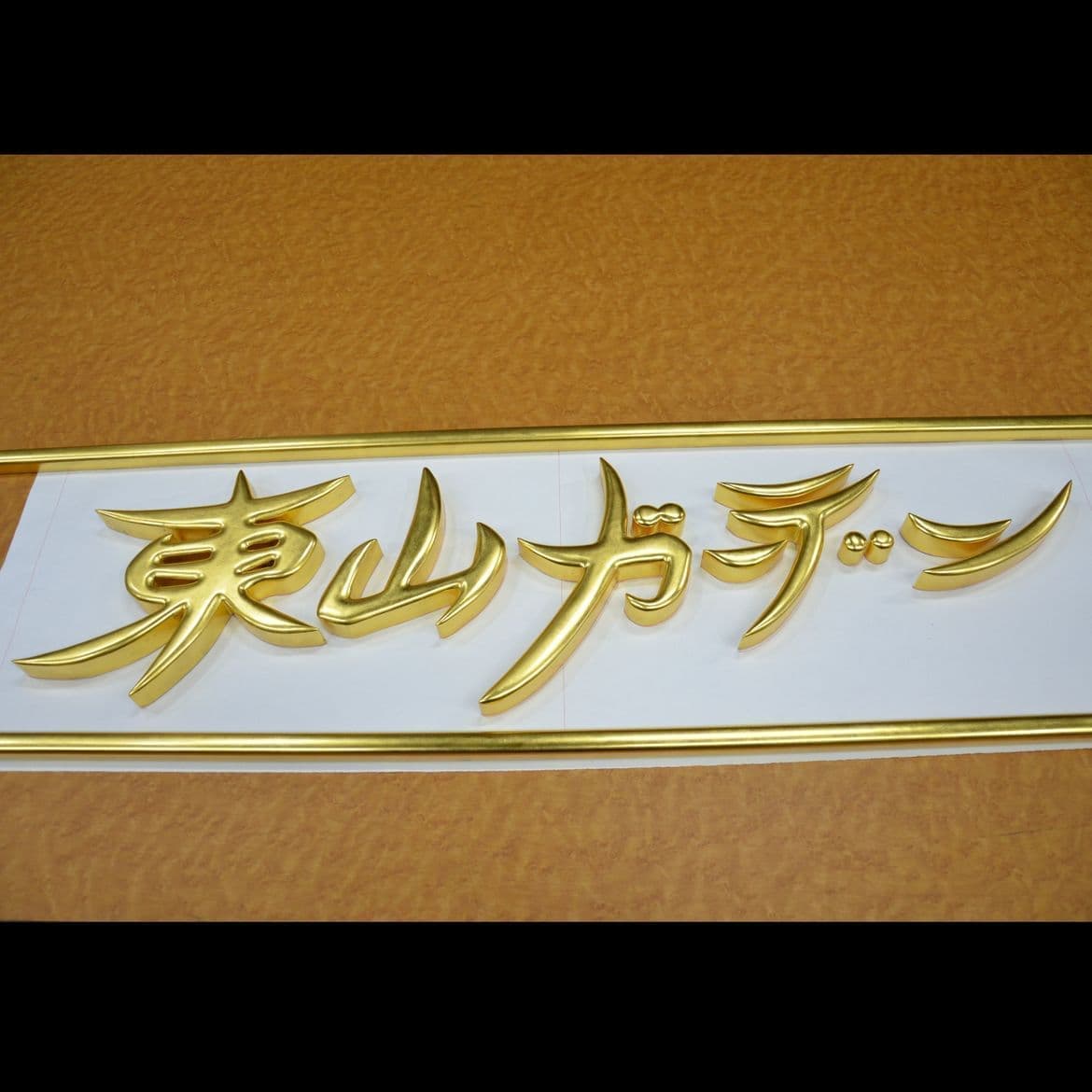 木製の切り抜き文字で金箔が前面に貼ってある看板