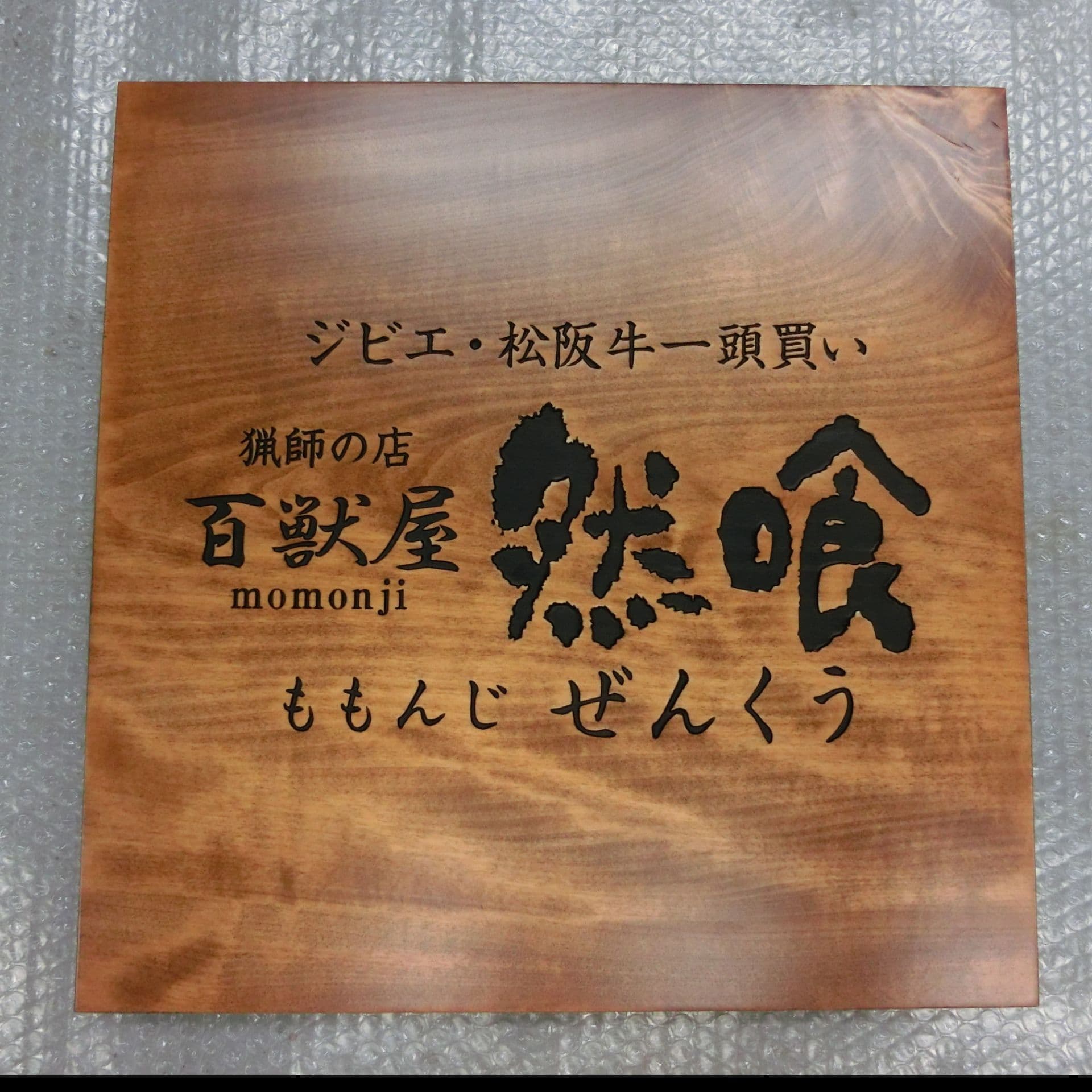 木目のきれいな板に黒文字で彫ってある看板