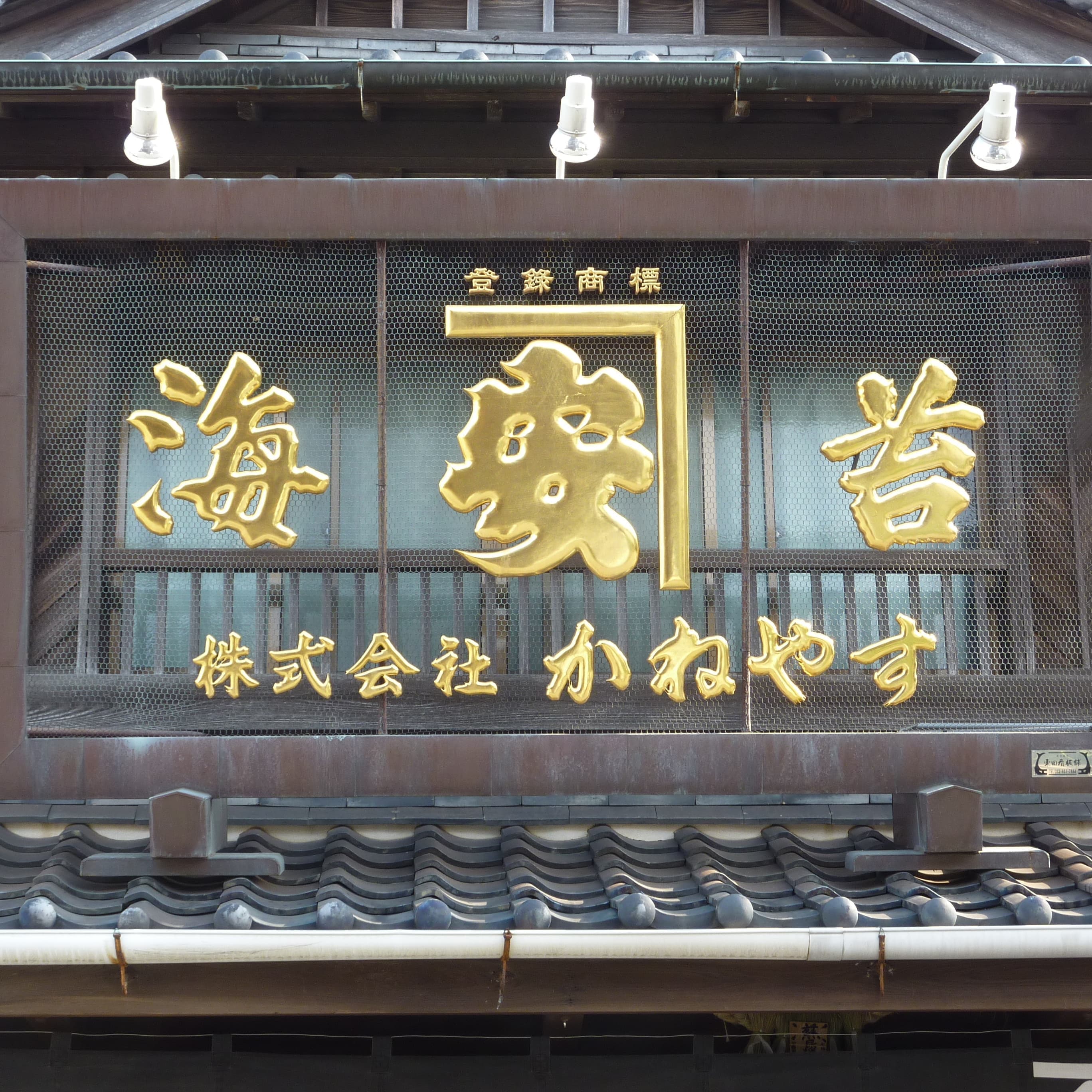 入り口の上に銅の枠、銅の網のベースに金の立体文字が昔からの感じの看板