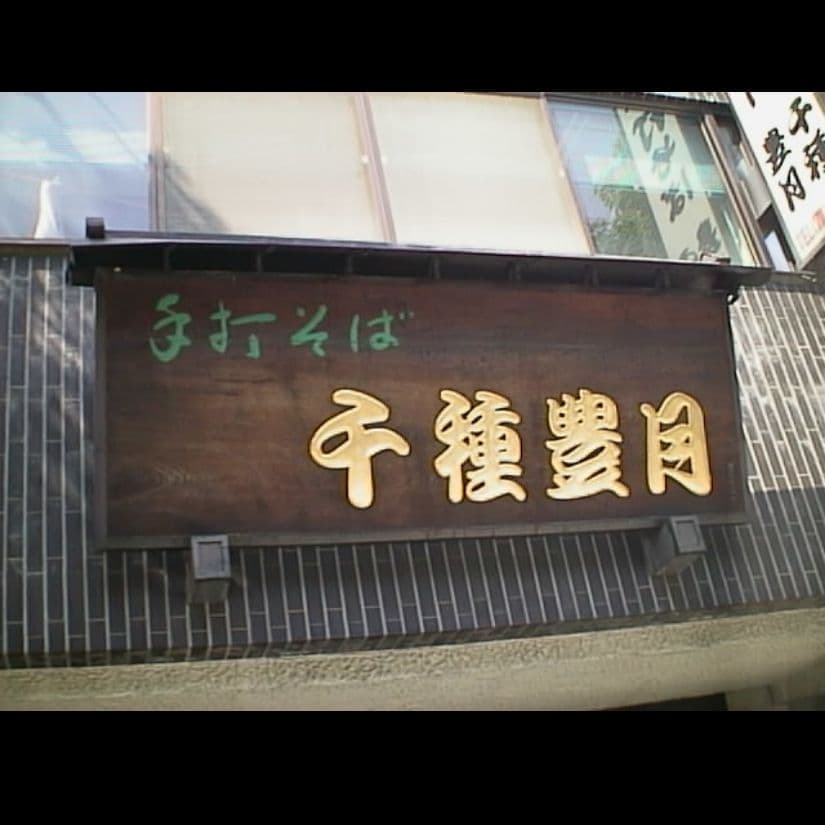壁に取り付けてある木製の板に金色に彫刻した文字が老舗のそばの名店の看板
