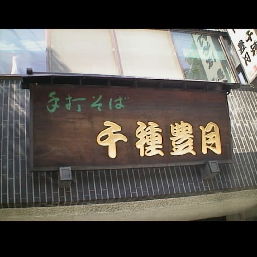 壁に取り付けてある木製の板に金色に彫刻した文字が老舗のそばの名店の看板