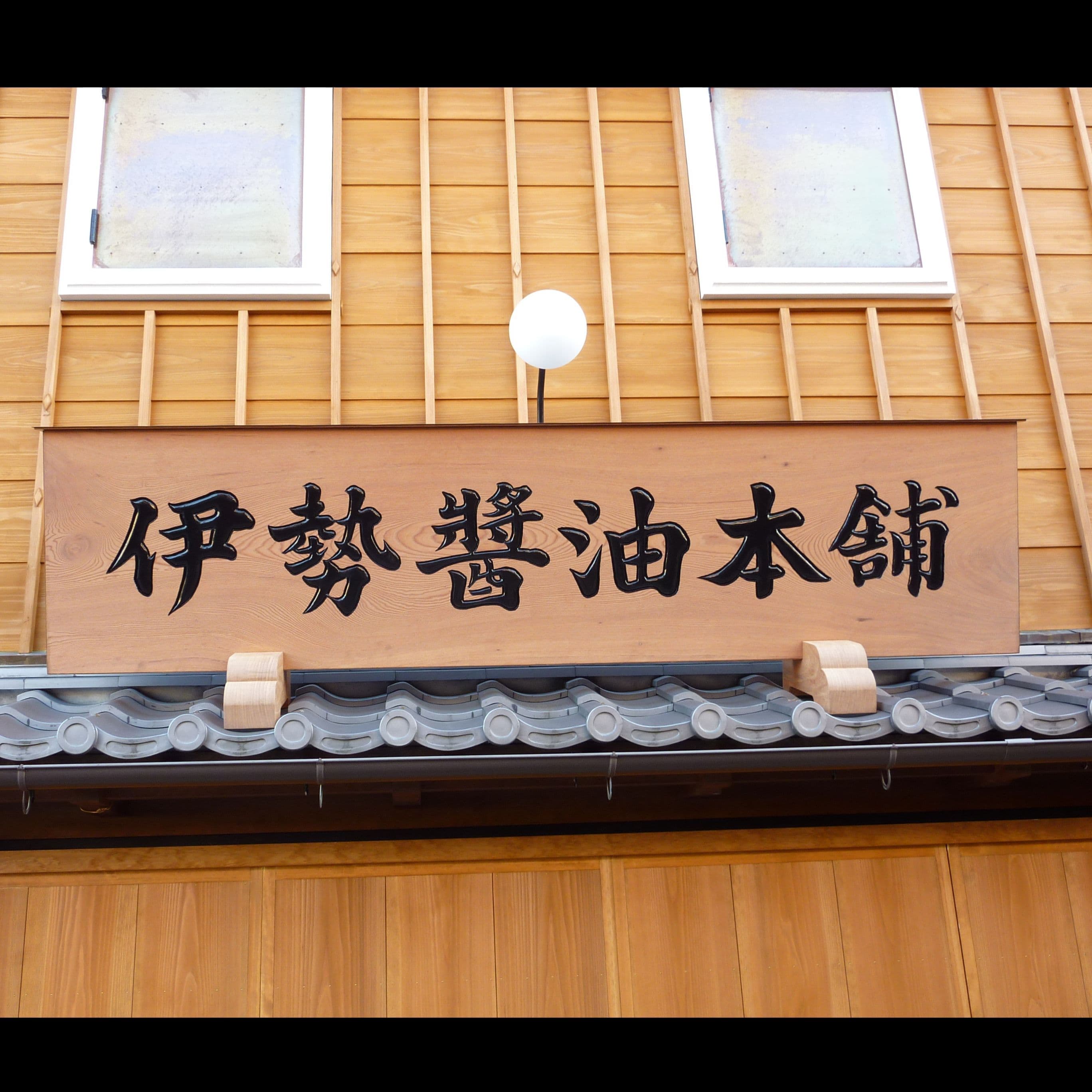 木造のお店にふさわしい木の看板で黒の彫り文字の看板