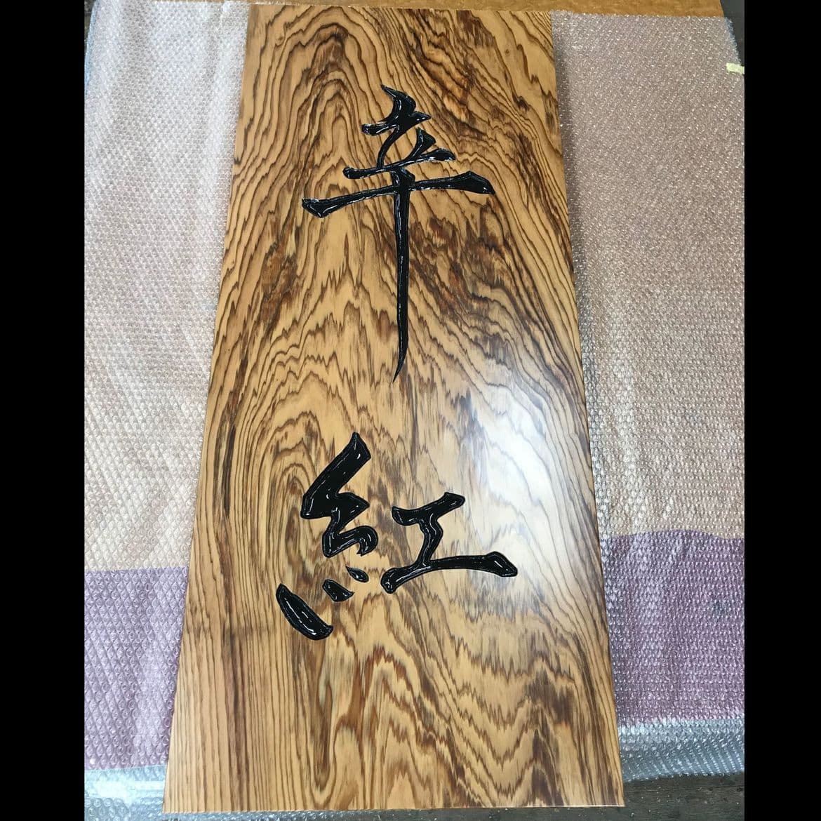 不燃材の杉板に黒文字を彫刻したラーメン店の看板