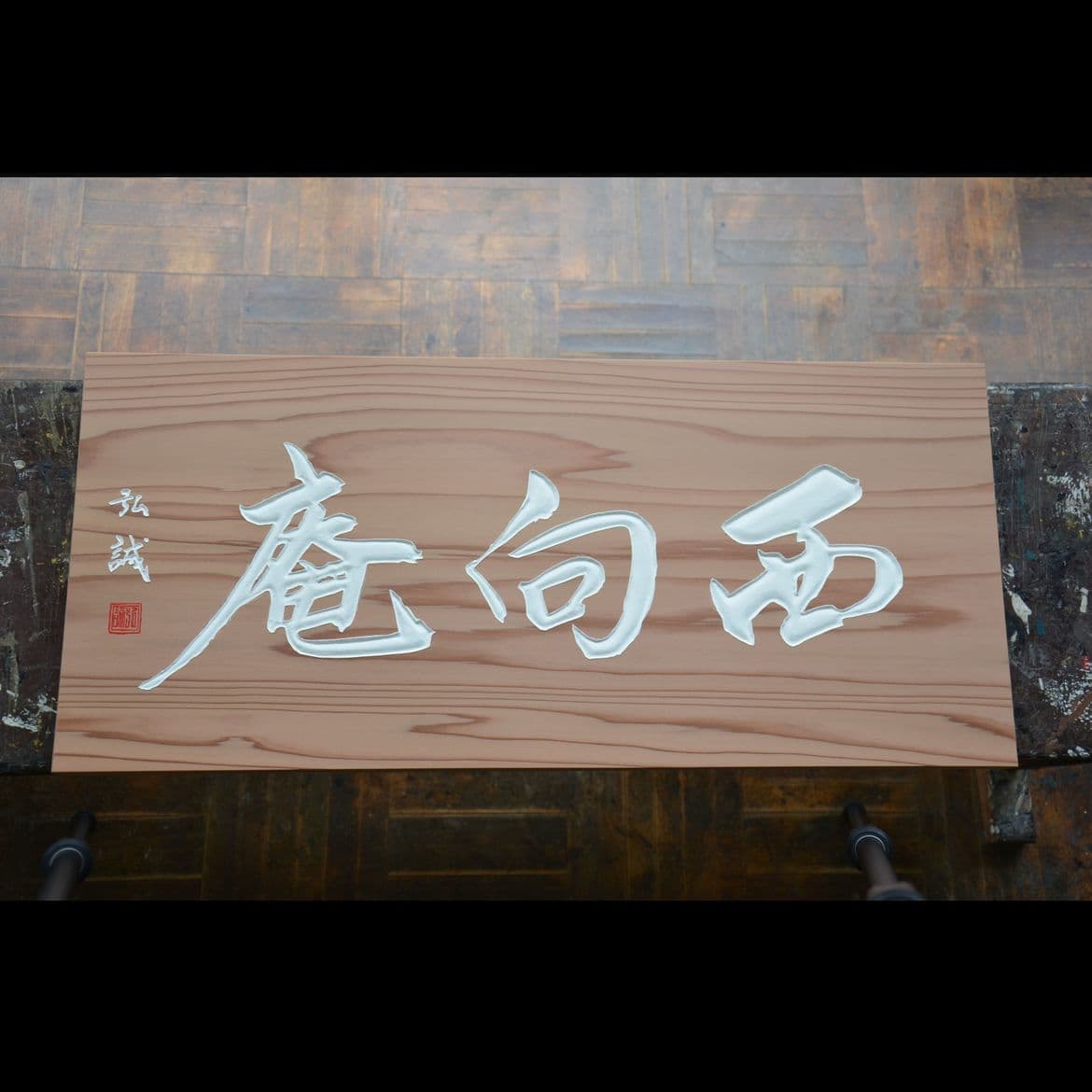 杉の木の板に白い文字で茶室名と落款が書いてある彫刻看板、扁額