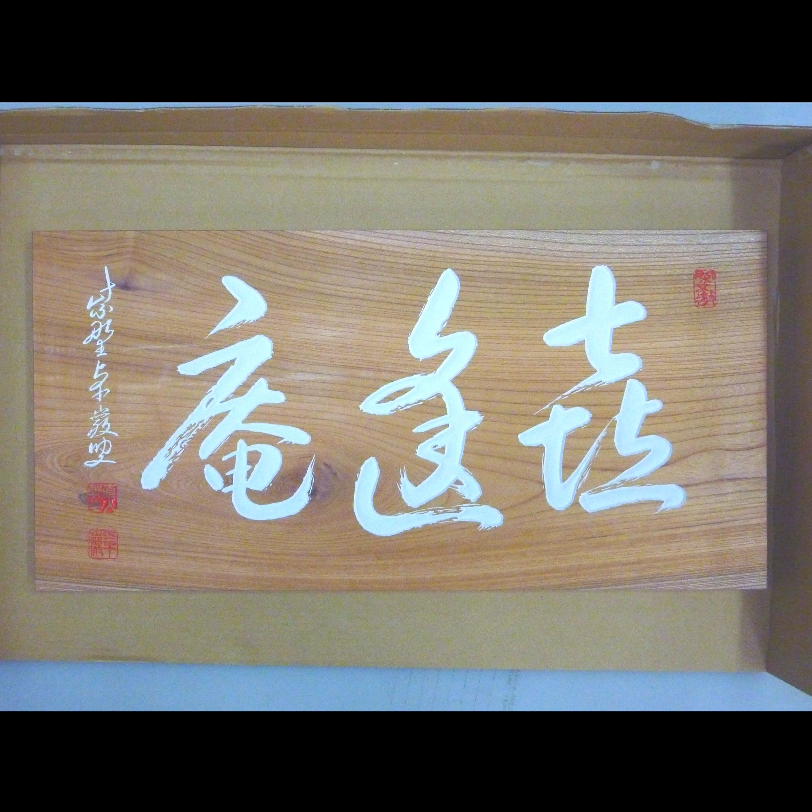 ケヤキの木の板に白い文字で茶室名と落款が書いてある彫刻看板、扁額
