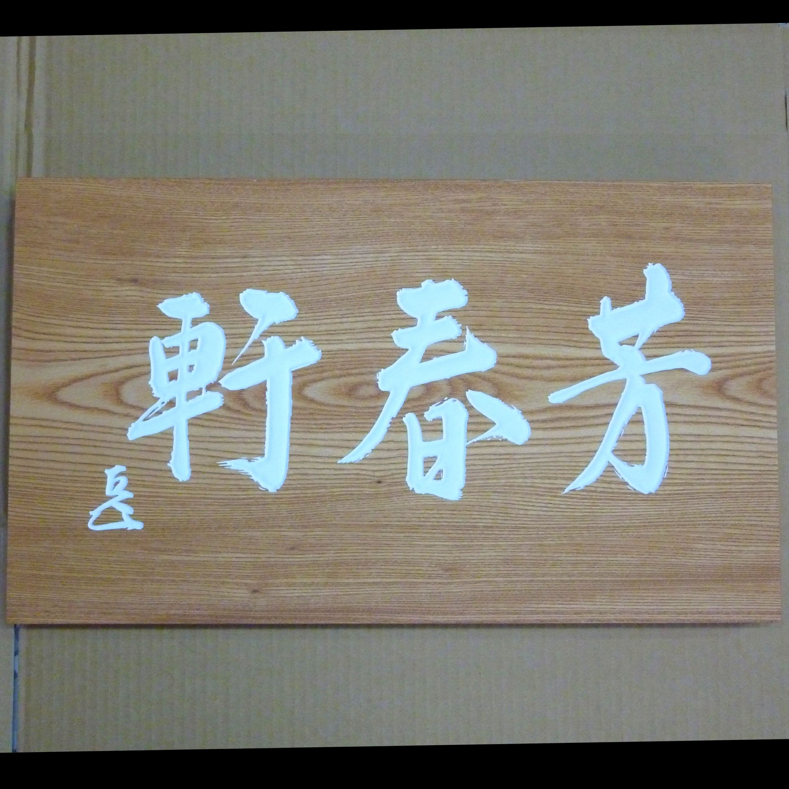 ケヤキの木の板に白い文字で茶室名と花押が書いてある彫刻看板、扁額