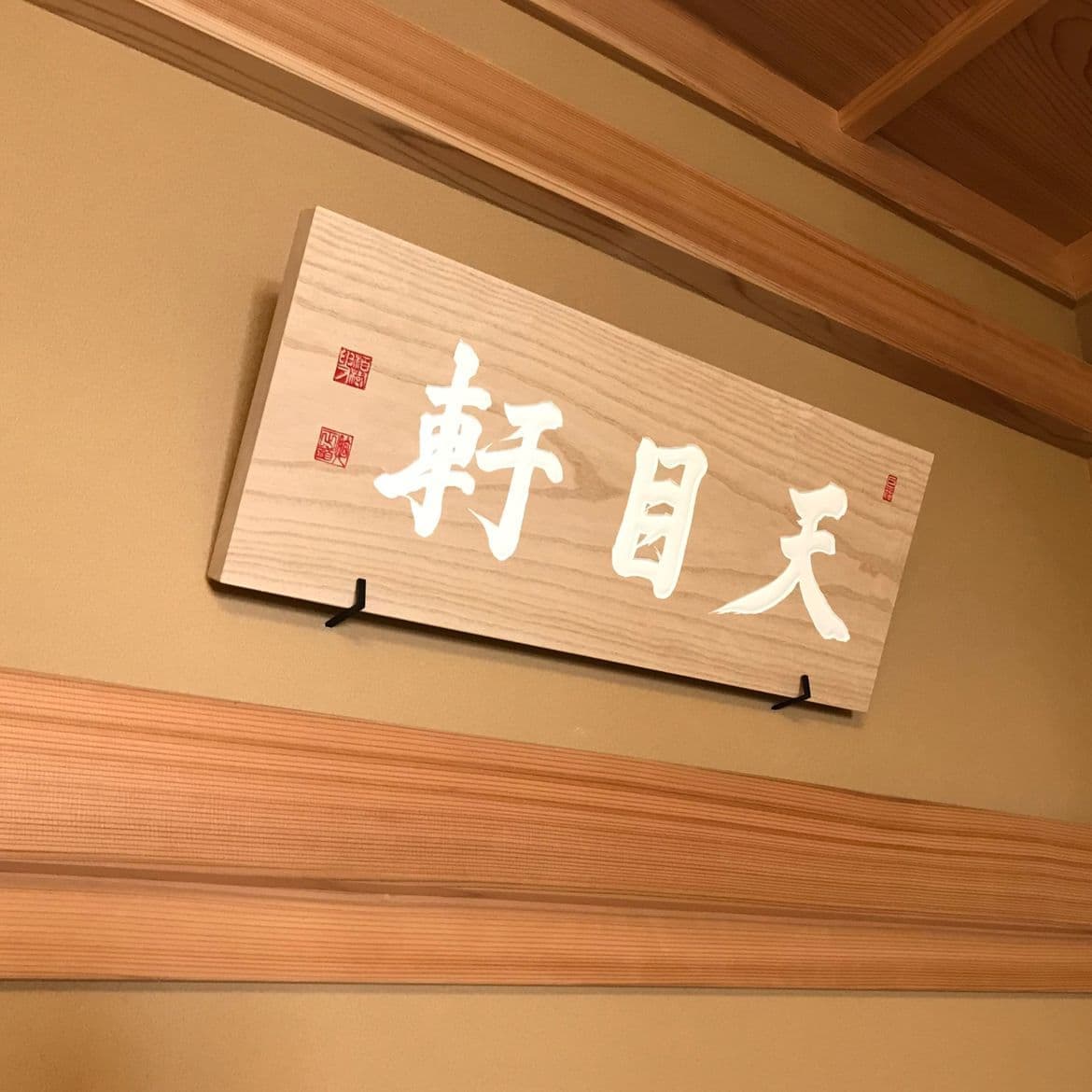 桐の木の板に白の文字で茶室名と落款が書いてある彫刻看板、扁額