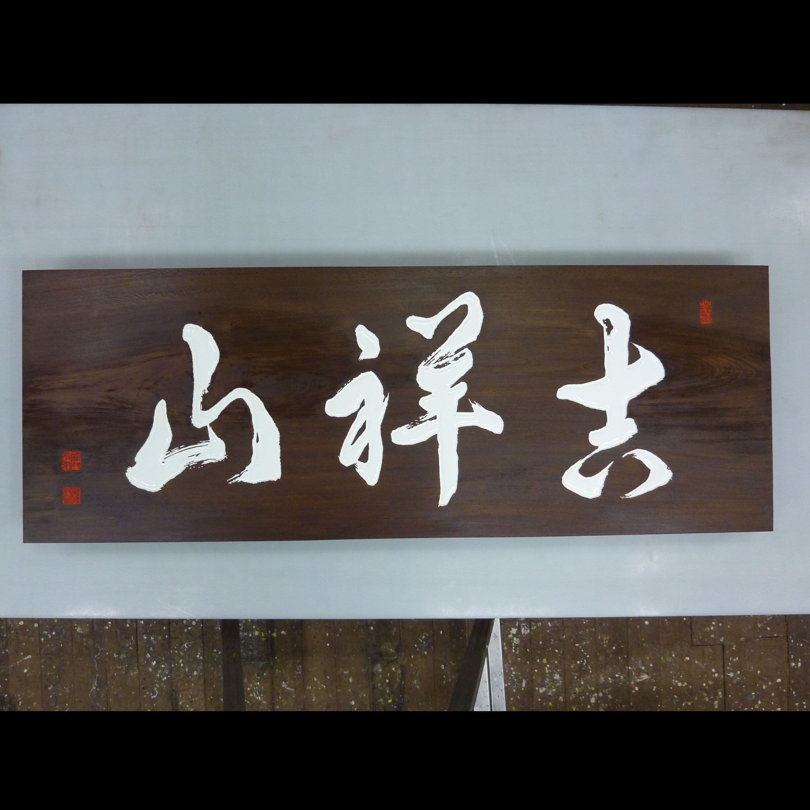 濃い色の木の板に白い文字の山号額、お寺の看板