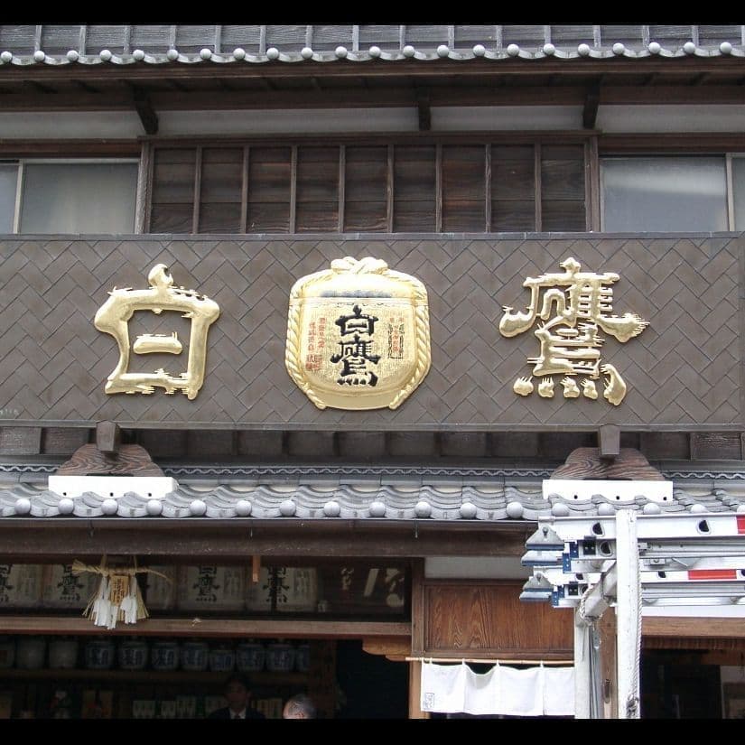 銅板金の台に金文字と金樽の酒販店の看板