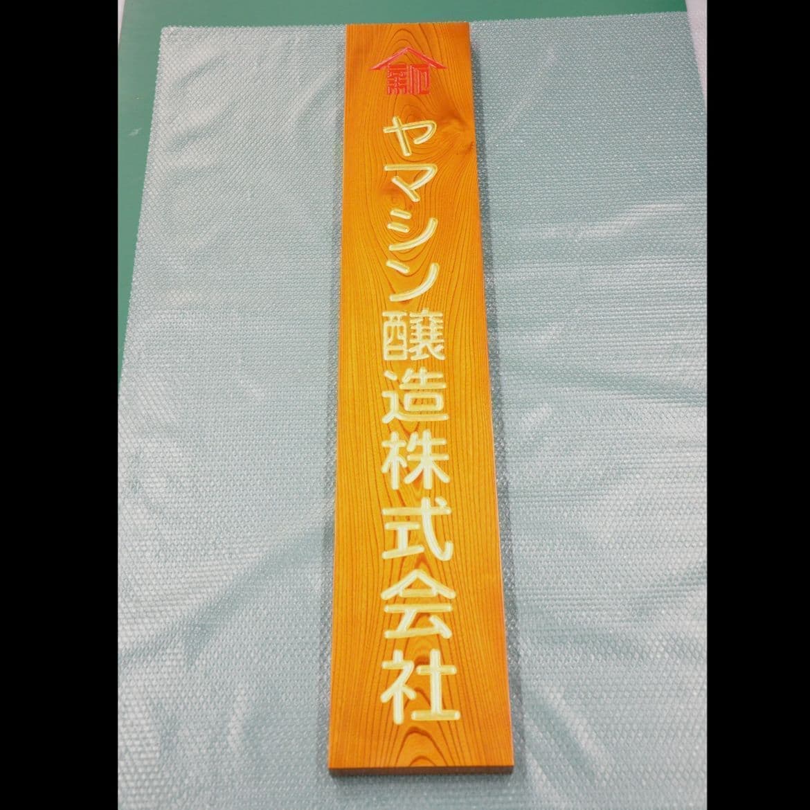 縦長の板に金文字で社名が彫ってある醸造会社の看板