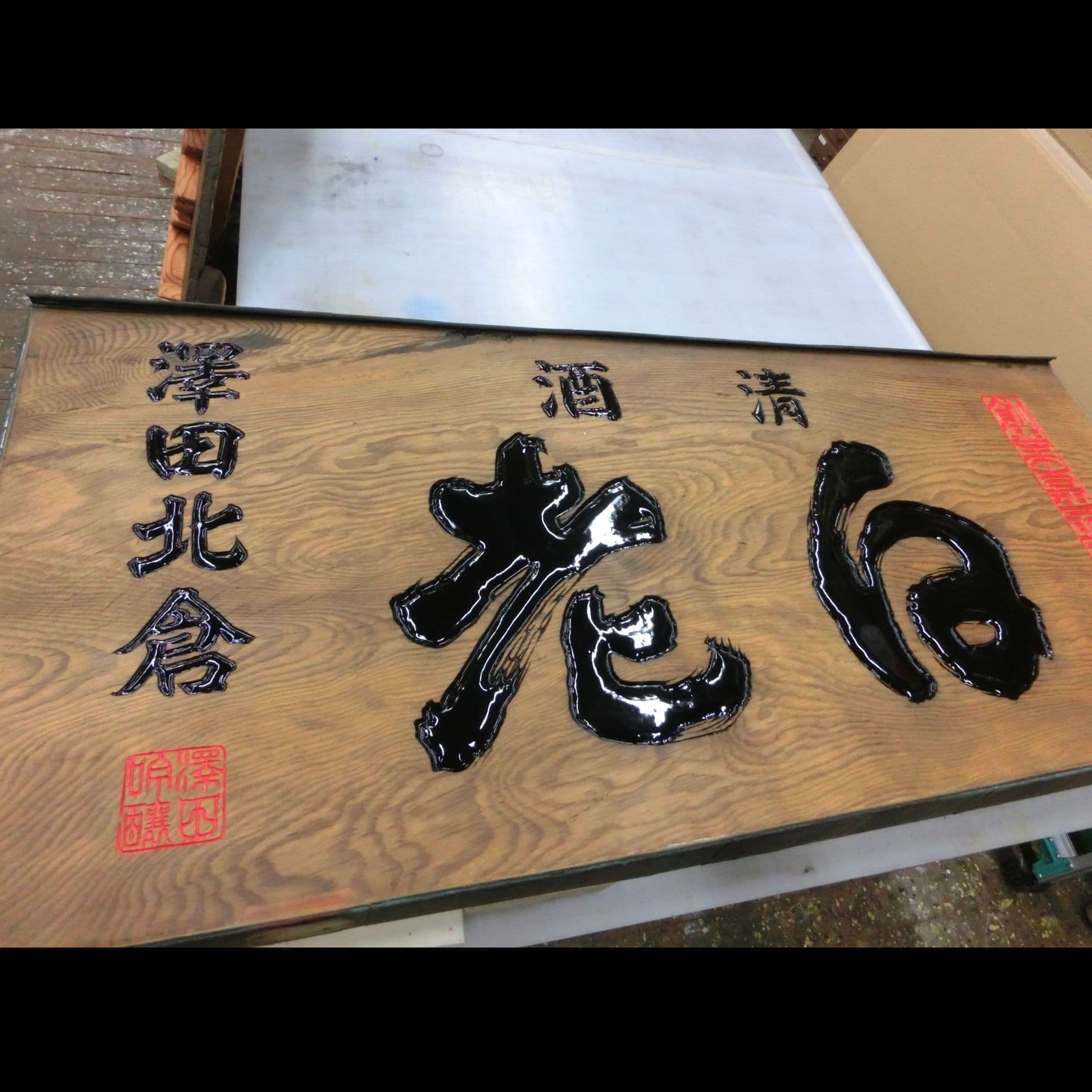大きな木の板に文字を彫ってある酒蔵の看板
