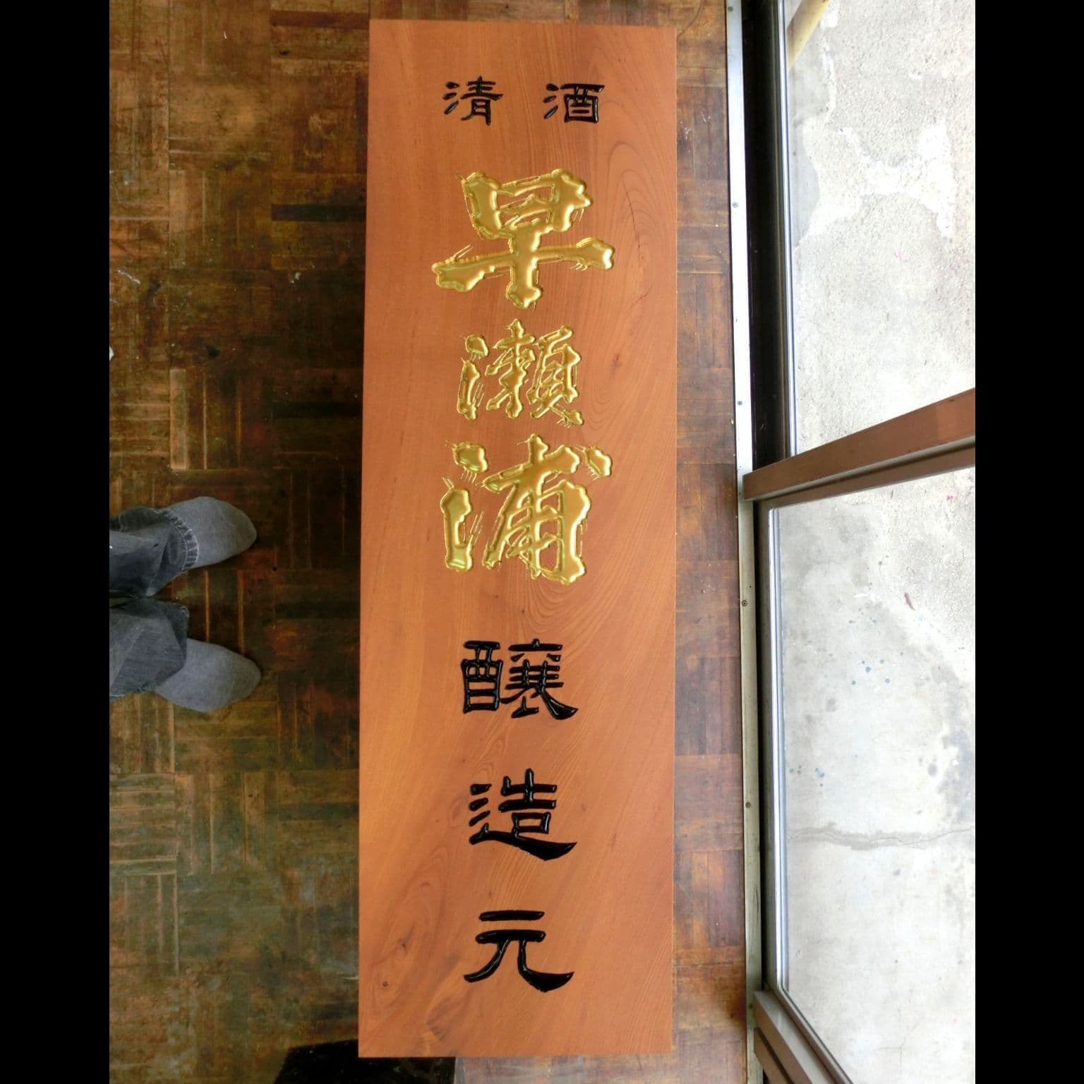 縦長の板にブランド名が金色で彫刻された日本酒蔵元の看板