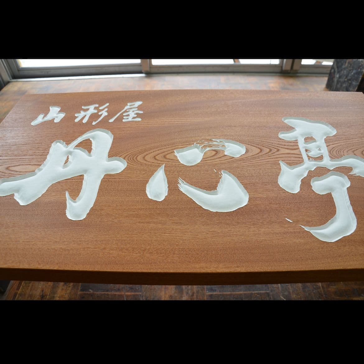 木の板に白い文字を彫刻した旅館の看板