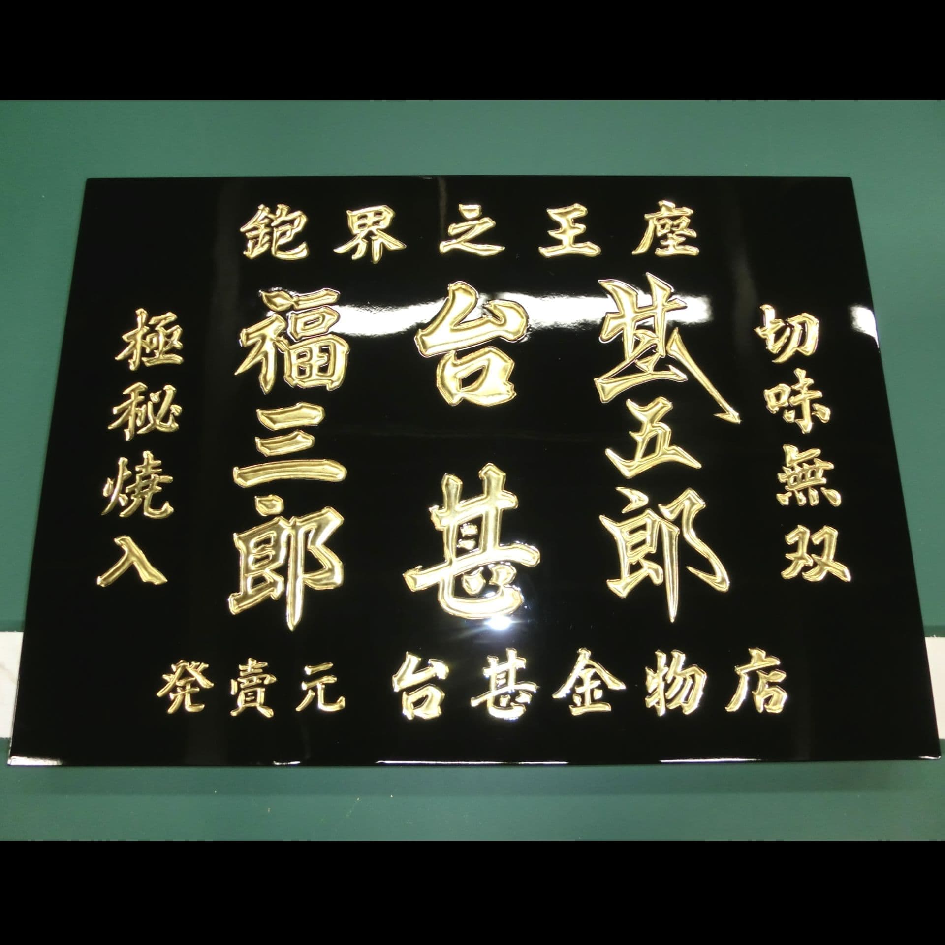 昭和の看板の修復、黒塗りの板に金文字が映える